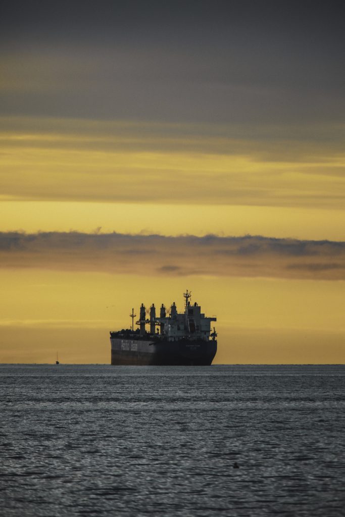 A large ship in the ocean at sunset.