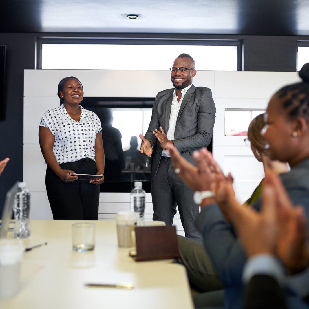 A group of business people clapping at a meeting.